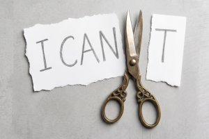 confidence coaching | Empower Me Hub Vintage scissors slice through torn papers showing'I CAN' and 'T', symbolizing turning 'I can't' into 'I can'.